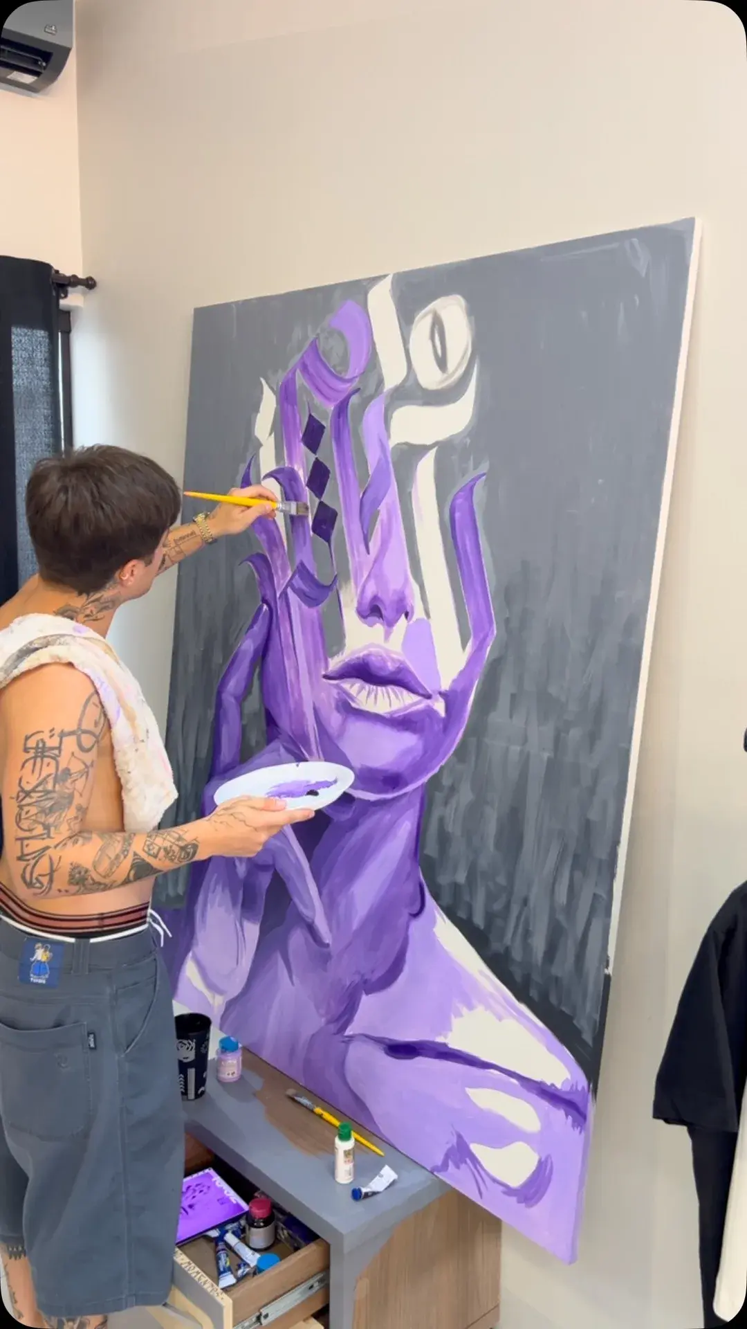Gabriel pintando um rosto roxo em tela