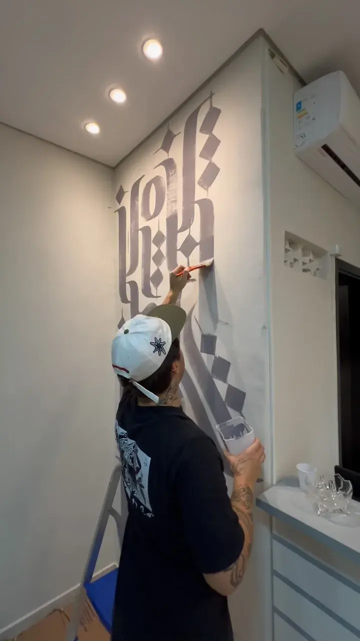 Gabriel pintando caligrafia em uma parede