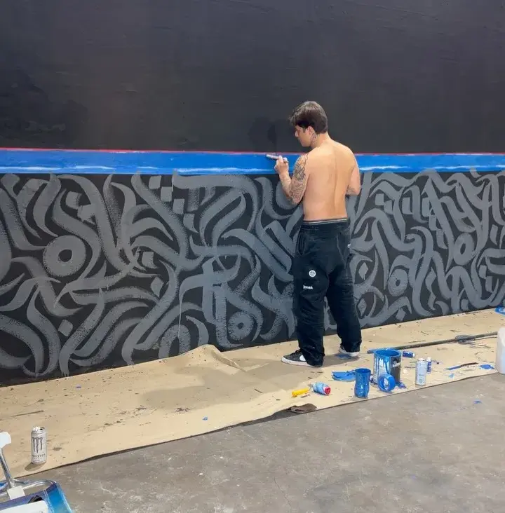 Gabriel pintando uma parede com caligrafia, foto em preto e branco