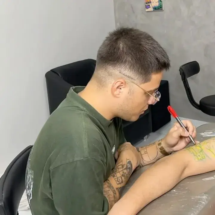 Gabriel tatuando, de camisa verde