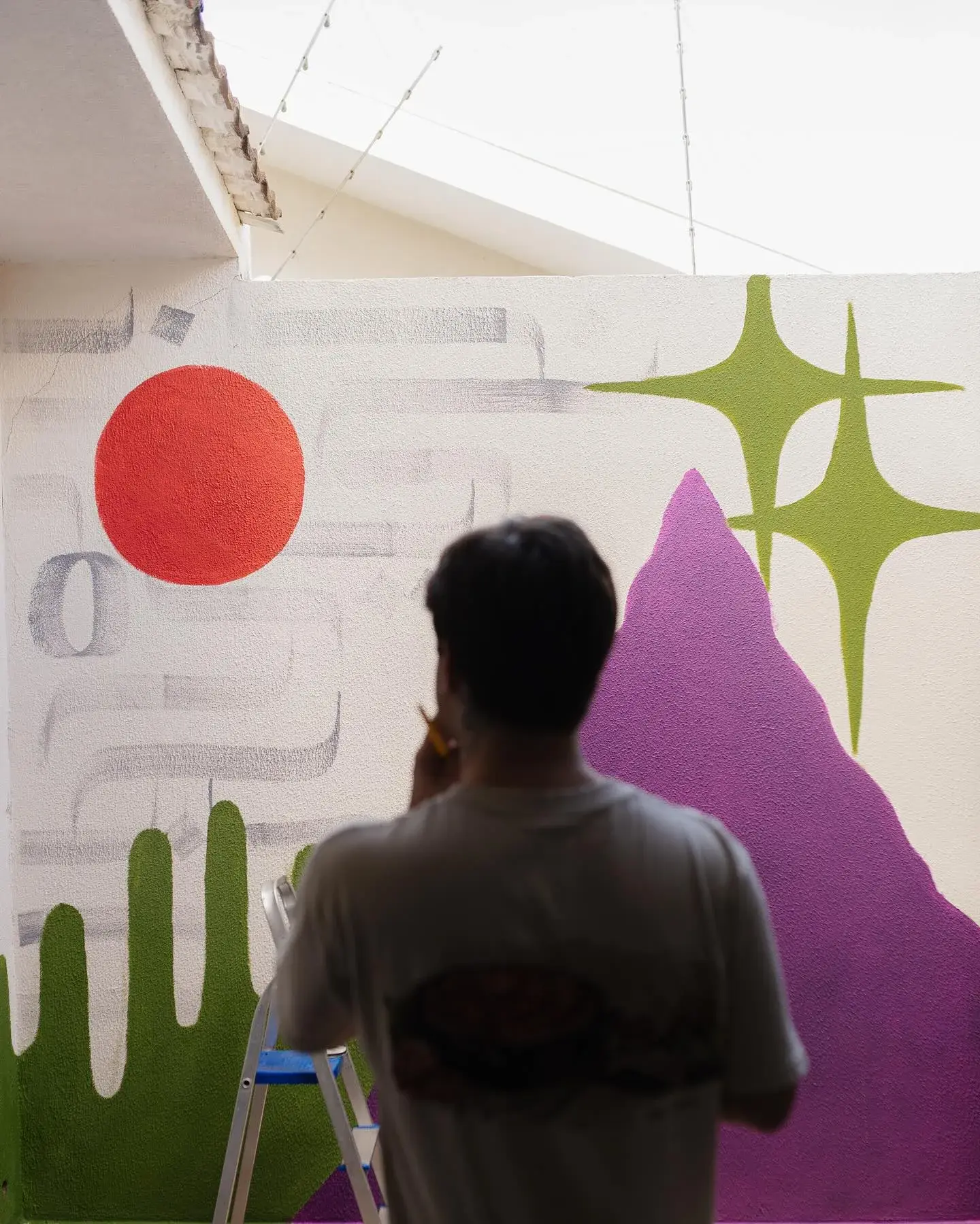 Mural colorido com sol vermelho, formas verdes e roxas