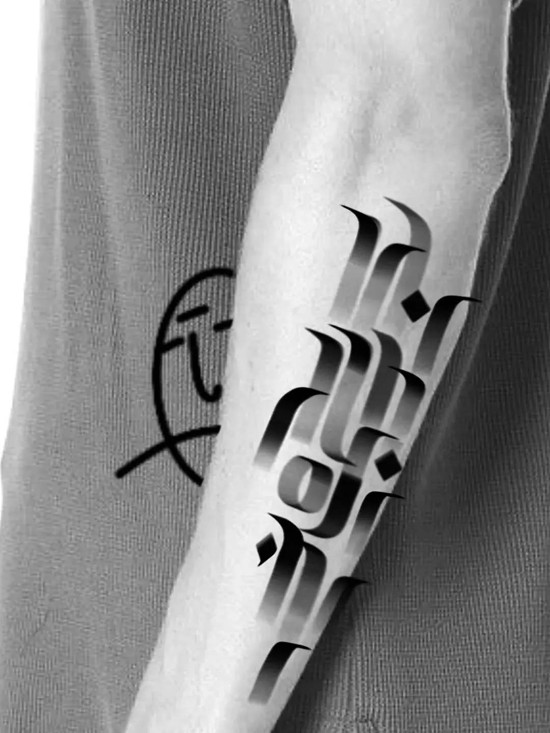Detalhe da caligrafia tatuada no braço, preto e branco