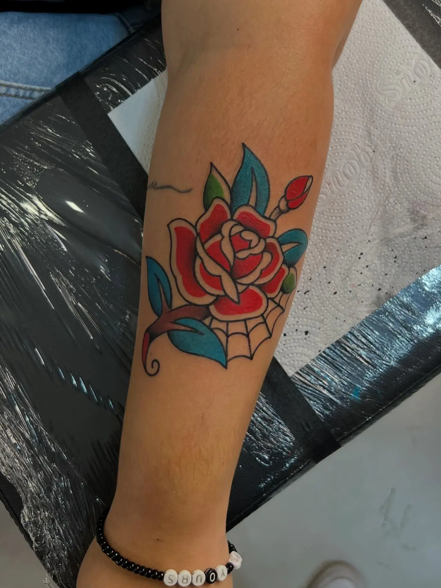 Rosa traditional colorida tatuada no antebraço