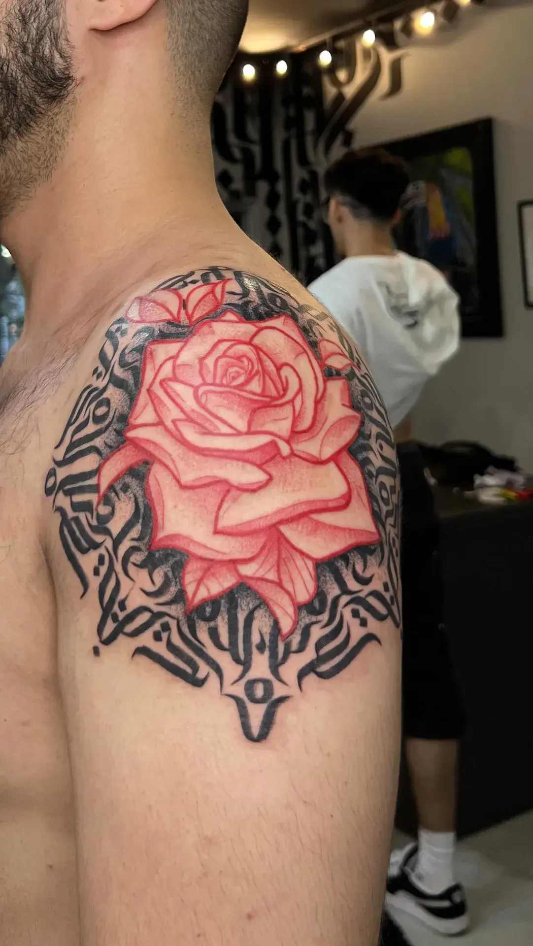 Rosa vermelha com ornamentos pretos tatuada no ombro